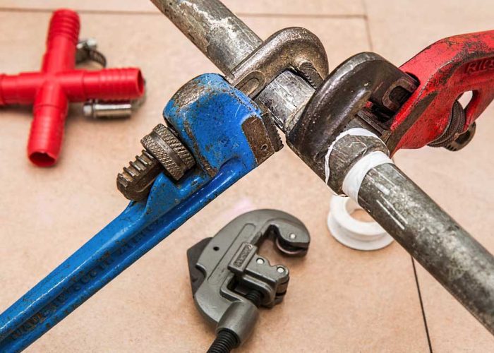 Outils de plomberie professionnelle, incluant des clés serre-tubes rouge et bleue, utilisés par les experts en assainissement dans le Hainaut.